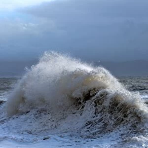 Huge waves crash against a stone jetty at Criccieth, Gwynedd, Wales, United Kingdom
