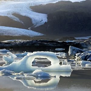 Ice arch among icebergs floating on Fjallsarlon lagoon, near Jokulsarlon, South Iceland
