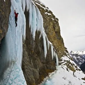 An ice climber ascending a frozen cascade in the Fournel Valley, Ecrins Massif, France