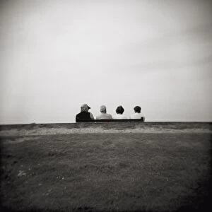 Image taken with a Holga medium format 120 film toy camera of four people on a bench overlooking the sea, Freshwater Bay, Isle of Wight, Hampshire, England, United