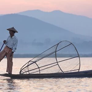 Intha leg rowing fishermen at dawn on Inle Lake who row traditional wooden boats using their leg and fish using nets stretched over conical bamboo frames, Inle Lake, Myanmar (Burma), Southeast Asia