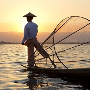 Intha leg rowing fishermen at sunset on Inle Lake who row traditional wooden boats using their leg and fish using nets stretched over conical bamboo frames, Inle Lake, Myanmar (Burma), Southeast Asia