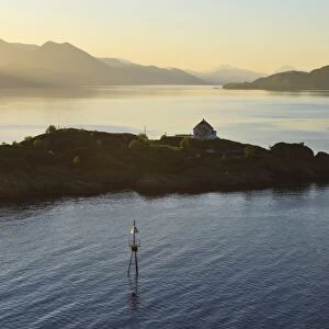 Islet with house lit by shafts of sunlight at dawn, entrance to Romsdalsfjord, Norway, Scandinavia, Europe