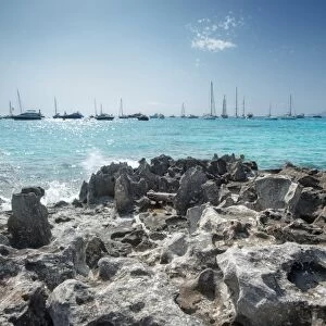 Jagged rocks with sailboats idling in the azure waters of Formentera, Balearic Islands