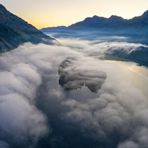 Lake Silvaplana and Sils hidden by the autumnal fog at dawn, aerial view by drone