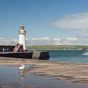 Lighthouse at entrance to outer harbour, motor yacht entering, Whitehaven