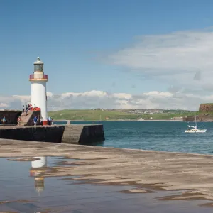 Lighthouse at entrance to outer harbour, motor yacht entering, Whitehaven