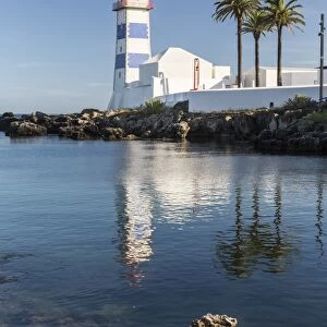 The lighthouse reflected in the blue water under the blue summer sky, Cascais, Estoril Coast