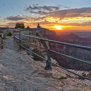 A lone hiker on Angels Window Overlook at Grand Canyon North Rim Arizona looking out at the sunrise