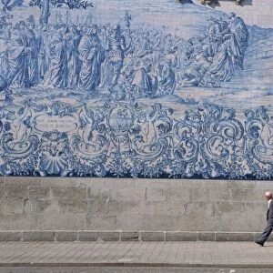 Man walks by the azulejo tile panel of the Carmo church in Oporto