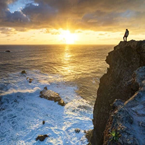One man watching sunrise over the ocean waves from cliffs, Madeira island, Portugal