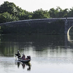 A man and woman fishing from a small boat in the moat around the Citadel in Hue, Vietnam