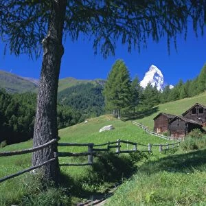 The Matterhorn towering above green pastures and wooden huts