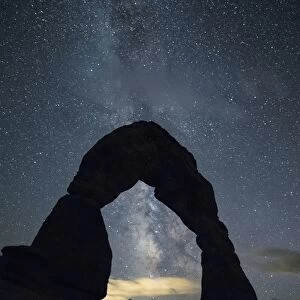 Milky Way and person under Delicate Arch, Arches National Park, Moab, Grand County