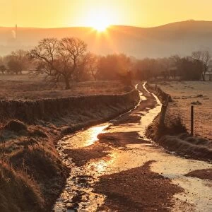 Misty and frosty sunrise over a country lane in winter, Castleton, Peak District National Park