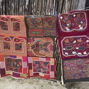 Molas hanging up for sale outside thatched house, Isla Tigre, San Blas Islands