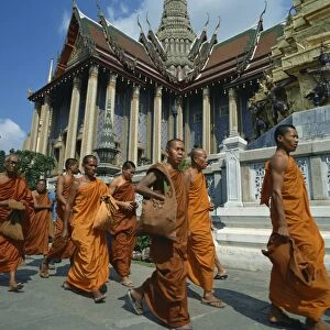Monks in saffron robes walk past a temple in Bangkok