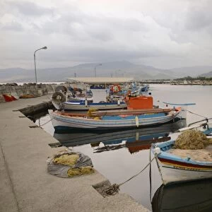 Moored fishing boats in Apothika village harbour, with clouds over mountains in the background