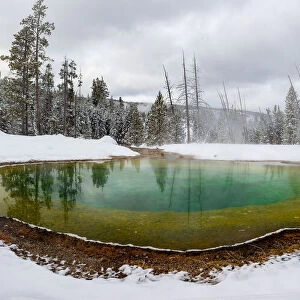 Morning Glory pool hot spring in the snow with reflections, Yellowstone National Park