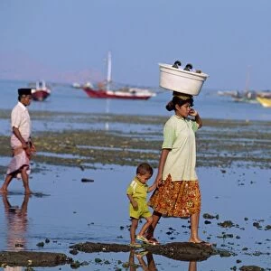 Mother and child walking at low tide off the port of Labuhanbajo