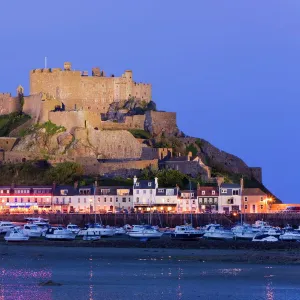 Mount Orgueil Castle, illuminated at dusk, overlooking Grouville Bay in Gorey