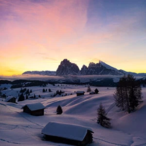 Mountain huts covered with snow at dawn with Sassopiatto and Sassolungo in background