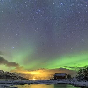The Northern Lights illuminates the wooden cabin, Oteren, Storfjorden, Lyngen Alps