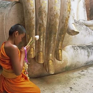 Novice Buddhist monk and Phra Atchana Buddha statue