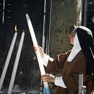 Nun lighting a candle at the Lourdes shrine, Lourdes, Hautes Pyrenees, France, Europe