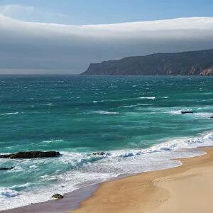 Ocean waves crashing on the sandy beach of Cascais, surrounded by cliffs, Estoril Coast