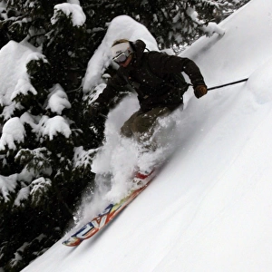 An off-piste skier in deep powder in the forests above Courmayeur and the east side of Mont Blanc