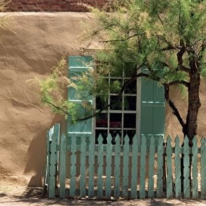 Detail of old adobe house with turquoise shutters and