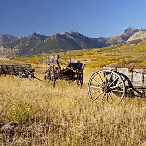 Old horse-drawn wagons with the Rocky Mountains in the Background, near Waterton