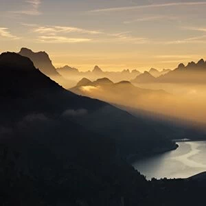 Orange light beam and mist on peaks of Dolomiti and Fedaia Pass, Cima Belvedere, Val di Fassa