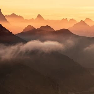 Orange sky at dawn and mist on peaks of Dolomites and Fedaia Pass, Cima Belvedere
