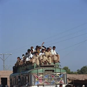 Overloaded bus with men riding on the roof near Multan in Pakistan