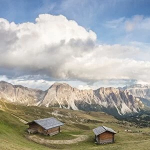 Panorama of green meadows and huts of the Odle mountain range seen from Seceda, Val Gardena