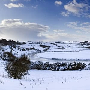 Panoramic view of snow-covered landscape beneath blue winter sky looking towards meandering River Aln, Lesbury, near Alnwick, Northumberland, England, United