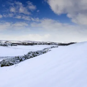 Panoramic view of snow-covered landscape beneath blue winter sky looking towards meandering River Aln, Lesbury, near Alnwick, Northumberland, England, United