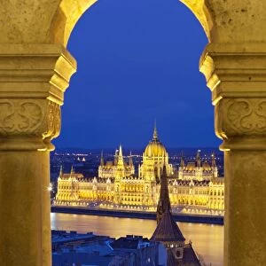 Parliament (Orszaghaz) through arches of Fishermens Bastion (Halaszbastya) at dusk, UNESCO World Heritage Site, Budapest, Hungary, Europe