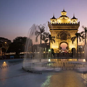 Patuxai Victory Monument (Vientiane Arc de Triomphe) and fountain floodlit at dusk