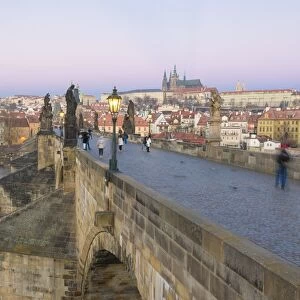 People on the historical Charles Bridge on Vltava River at dawn, UNESCO World Heritage Site