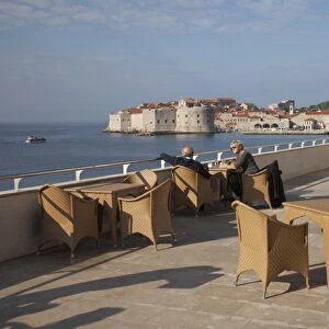People relaxing on terrace of Excelsior Hotel with Dubrovnik Old Town in the distance, Dubrovnik, Croatia, Europe