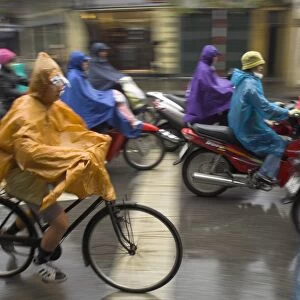 People riding bikes and mopeds in the rain wearing nylon protection