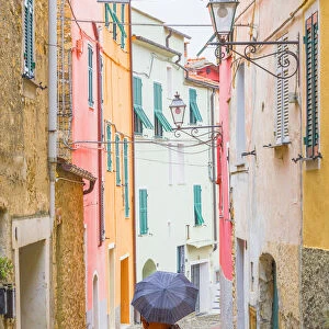 A person with an umbrella in the main street of Civezza, Province of Imperia, Liguria