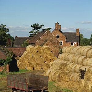 Piles of straw bales and a trailer outside a farm house on an afternoon in autumn near Kingsbury