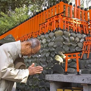 Pilgrim praying at altar with miniature orange toriis in background