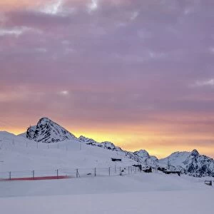 Pink clouds and snow frame the Bernina Express train at dawn, Bernina Pass, Canton of Graubunden