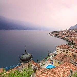 Pink sunrise lights up Lake Garda and the typical town of Limone Sul Garda, province of Brescia