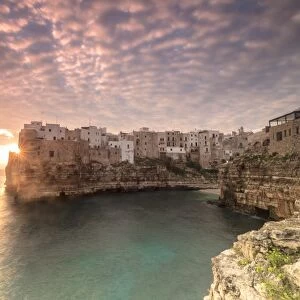 Pink sunrise on the turquoise sea framed by old town perched on the rocks, Polignano a Mare